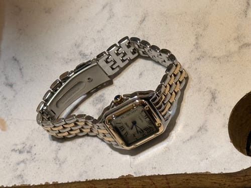 Close-up of the two-toned Grealy De Mains watch, showing the detailed band and clasp on a table.