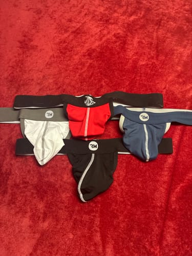 Reviewer's assortment of colorful Strapless Jocks laid out on a red surface.