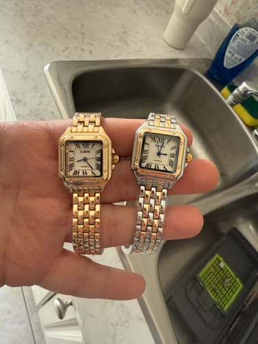 Customer holding two classic Grealy De Mains watches, one gold-toned and one two-toned, in their hand.