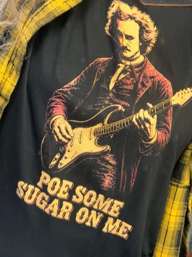 Customer wearing the black Poe Some Sugar On Me T-Shirt with a graphic of Edgar Allan Poe playing an electric guitar.