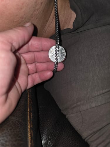 Close-up of a customer's hand holding a dime next to the Cuban Link Chain to show the link size.