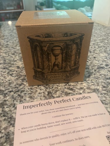 Customer's photo showing the brown cardboard box for The Monument candle on a granite countertop.