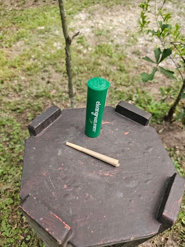 Customer's single Cherry Dosi Do Pre-Roll and its green tube on an outdoor table.