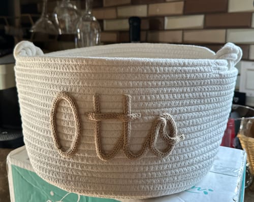 Customer's white Personalized Knitted Basket with the name 'Otto' in tan yarn, sitting on a box.