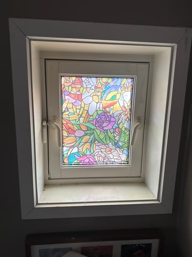 Kunde viser Tulia vindusfolie med fargerikt blomstermotiv på et soveromsvindu.