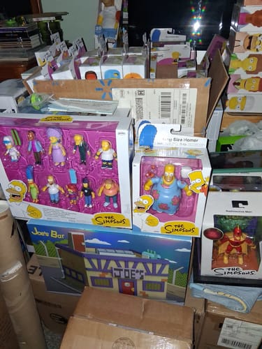 Reviewer's King Sized Homer action figure in its box, shown amidst a large collection of other Simpsons merchandise.