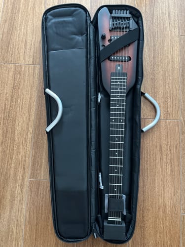 Kunde zeigt die kopflose Donner HUSH X E-Gitarre in ihrer geöffneten schwarzen Tragetasche.