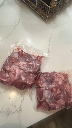 Customer's Qurbani lamb meat displayed in two clear, vacuum-packed bags on a counter.