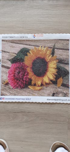 Rezensent zeigt das fertige Diamond Painting 'Sommer Blumen' mit einer Sonnenblume und einer rosa Blume.