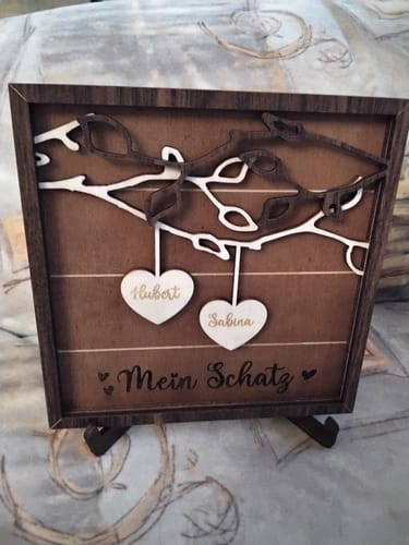 Kunde zeigt den Premium Aufsteller, der eine dekorative Holztafel mit personalisierten Herzen hält.