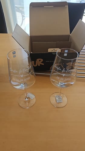Rezensent zeigt die zwei personalisierten Leonardo Gläser mit Gravur auf einem Tisch vor der geöffneten Verpackung.