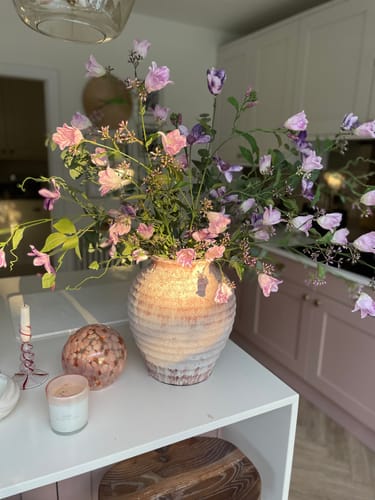 Customer's purple faux Bell Flower & Clematis arrangement in a decorative vase on a white kitchen counter.