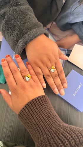Customer shows two hands, each wearing a matching Navae Birthstone Ring, highlighting the two-stone design.