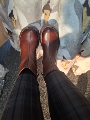 A top-down view of a reviewer wearing the chunky brown leather platform boots with plaid trousers.