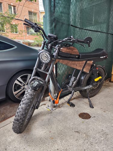 Customer's sturdy TIGER PLUS Electric Off Road Bike parked outdoors, showing its wood-look panels and thick tires.