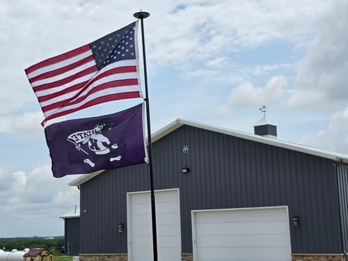 Customer's heavy duty American flag flying on a flagpole in front of a large gray building.