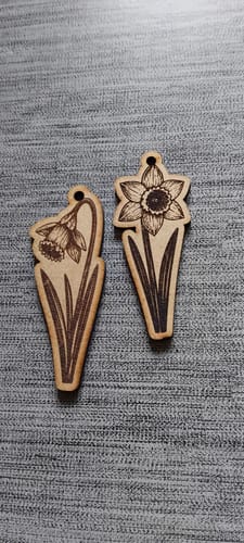 Reviewer shows two detailed wooden daffodil tags made with the AtomStack Swift laser engraver.