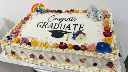 Customer's white sheet cake for a graduation, with a colorful border of freeze dried edible pansies.