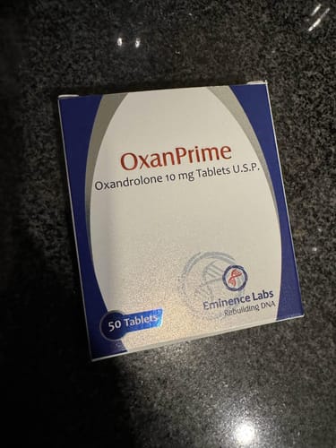 Un cliente muestra la caja del producto Oxanprime Oxandrolona sobre una superficie oscura.