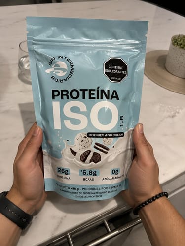 Cliente sosteniendo el empaque azul de la Proteína ISO en polvo, sabor Cookies & Cream.
