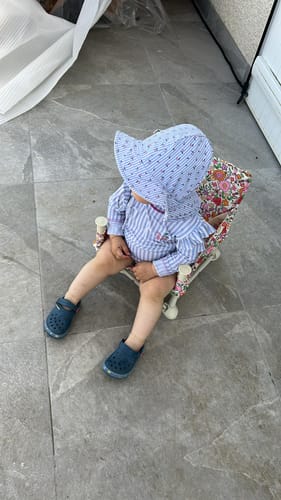 Reviewer's child sitting in their floral Paloma baby chair on a patio.