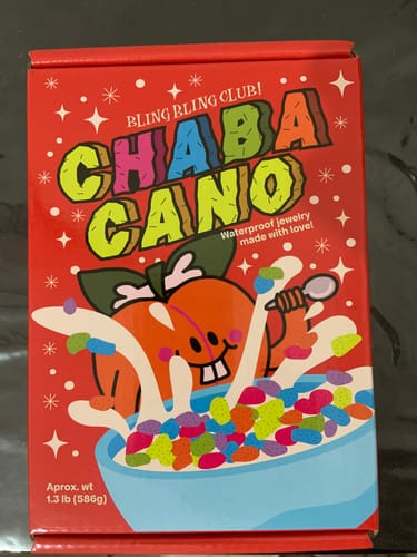 Empaque del Accesorio Sorpresa del cliente, una bonita caja roja con un diseño de cereal colorido.
