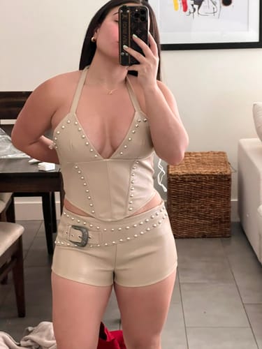Reviewer taking a mirror selfie in the beige, studded It girl stud set, showing the halter top and shorts.