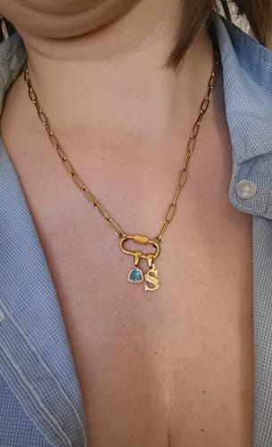 Customer wearing the gold Carabiner Charm Lock Necklace with an 'S' initial and blue birthstone charm.