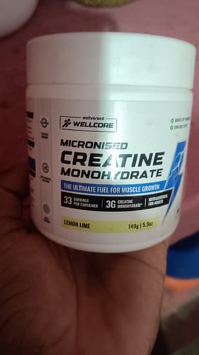 Customer holding a white container of Wellcore Micronised Creatine Monohydrate in the Lemon Lime flavor.