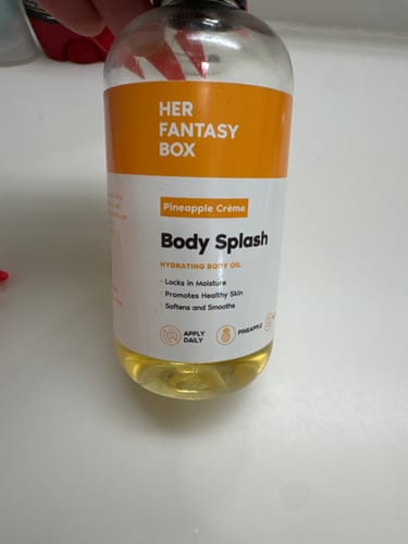 Reviewer holding a bottle of Her Fantasy Box Body Splash hydrating oil.