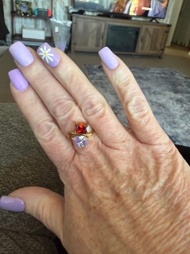 Customer's hand wearing the Navae Birthstone Ring with a vibrant red and a light purple stone.