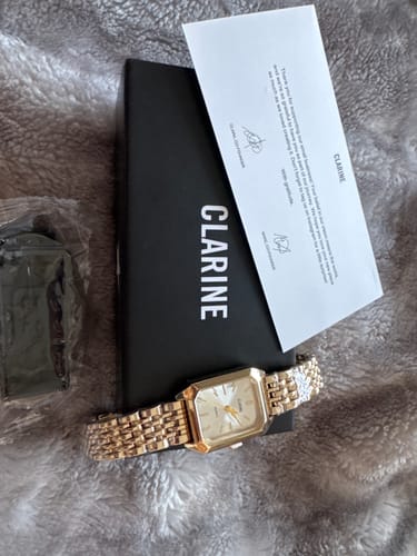 Customer's gold CLAIRE DE MAINS watch laid out with its black product box and a thank-you card.