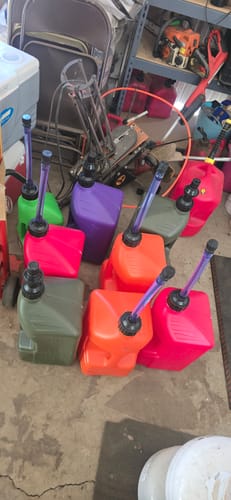Customer's large collection of colorful Tuff Jug 5 Gallon Jugs on a garage floor.