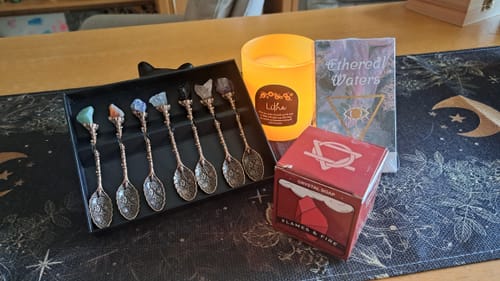 Ein Kunde zeigt Artikel aus der Witchy Box, darunter ein verziertes Löffelset, eine Kerze und eine Schachtel Seife.