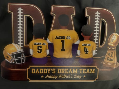 Customer's personalized 'Daddy's Dream Team' wooden plaque showing a father and two children from behind in custom jerseys.