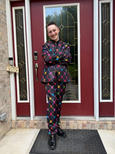 A person standing in a doorway wearing the full suit set with a colorful skull pattern.