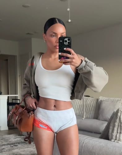 Reviewer taking a mirror selfie in a white Lucy Rib Top, showing its cropped fit with a grey hoodie.
