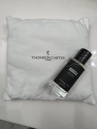 Customer's bottle of Smoke & Mirrors Eau de Parfum resting on a white, branded fabric pouch.