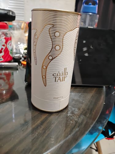 Reseñador muestra el envase cilíndrico del perfume Riiffs TAIF sobre una mesa.