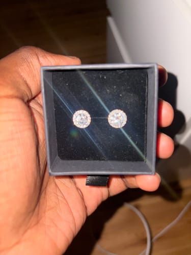 Customer holding a black box showing a pair of sparkling Moissanite Halo Earrings.