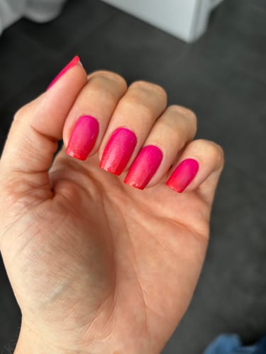 Hand einer Rezensentin, die die 'Hot Ombré' UV-Gelfolien mit einem leuchtenden Rosa-Rot-Verlauf trägt.