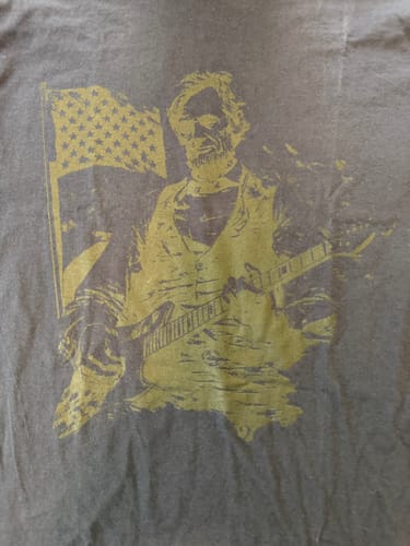Close-up of the reviewer's Lincoln Riff T-Shirt with a faded, single-color graphic and missing text at the bottom.