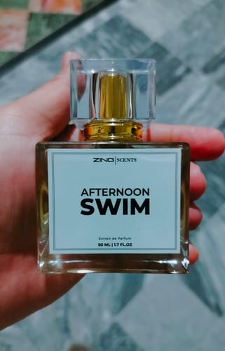 Customer holding the square glass bottle of Afternoon Swim fragrance against a tiled background.