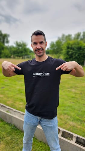 Customer showing the fit and design of the black Stanislav Tee while standing outside.