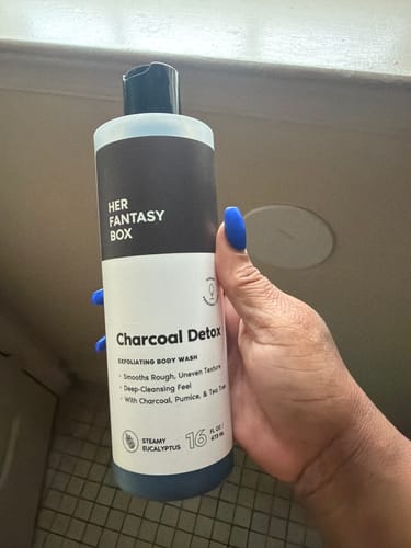 Customer holding a bottle of the Charcoal Detox Exfoliating Body Wash.