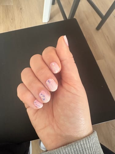 Hand einer Kundin mit den UV Gel Babyboomer Nude Folien, verziert mit Glitzer und Herzen.