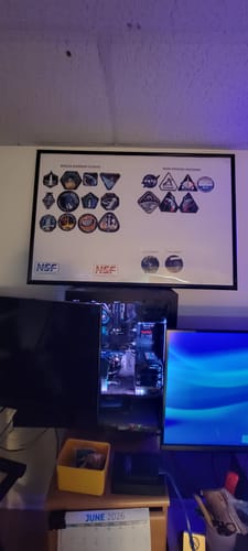 Customer's framed display of various space flight patches hanging on a wall above a computer desk.