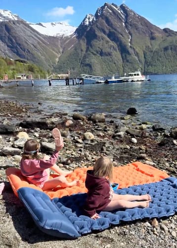 Kids relaxing on the Adventure Mat by the lake