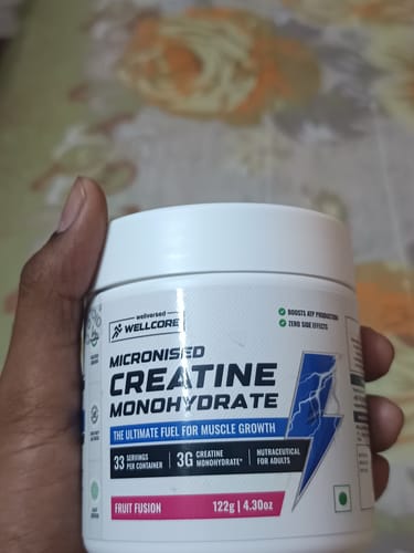 Customer holding a white tub of Wellcore Micronised Creatine Monohydrate in Fruit Fusion flavor.