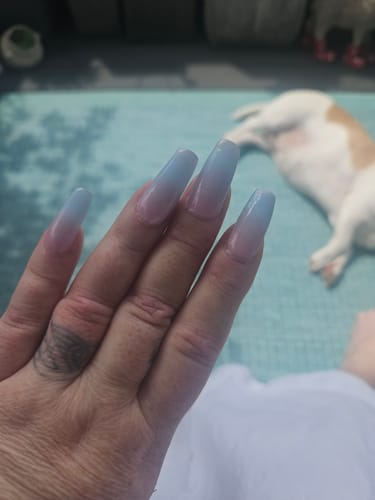 Hand einer Kundin mit langen Nägeln, die die Candy Sorbet UV Gel Nail Wraps mit rosa-blauem Ombré-Design trägt.